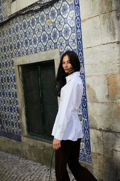 girl wearing white button up shirt standing side ways