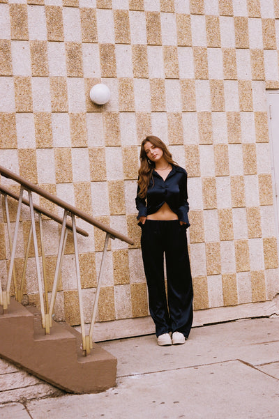 girl standing up wearing roma silk pants and borro silk button up in navy