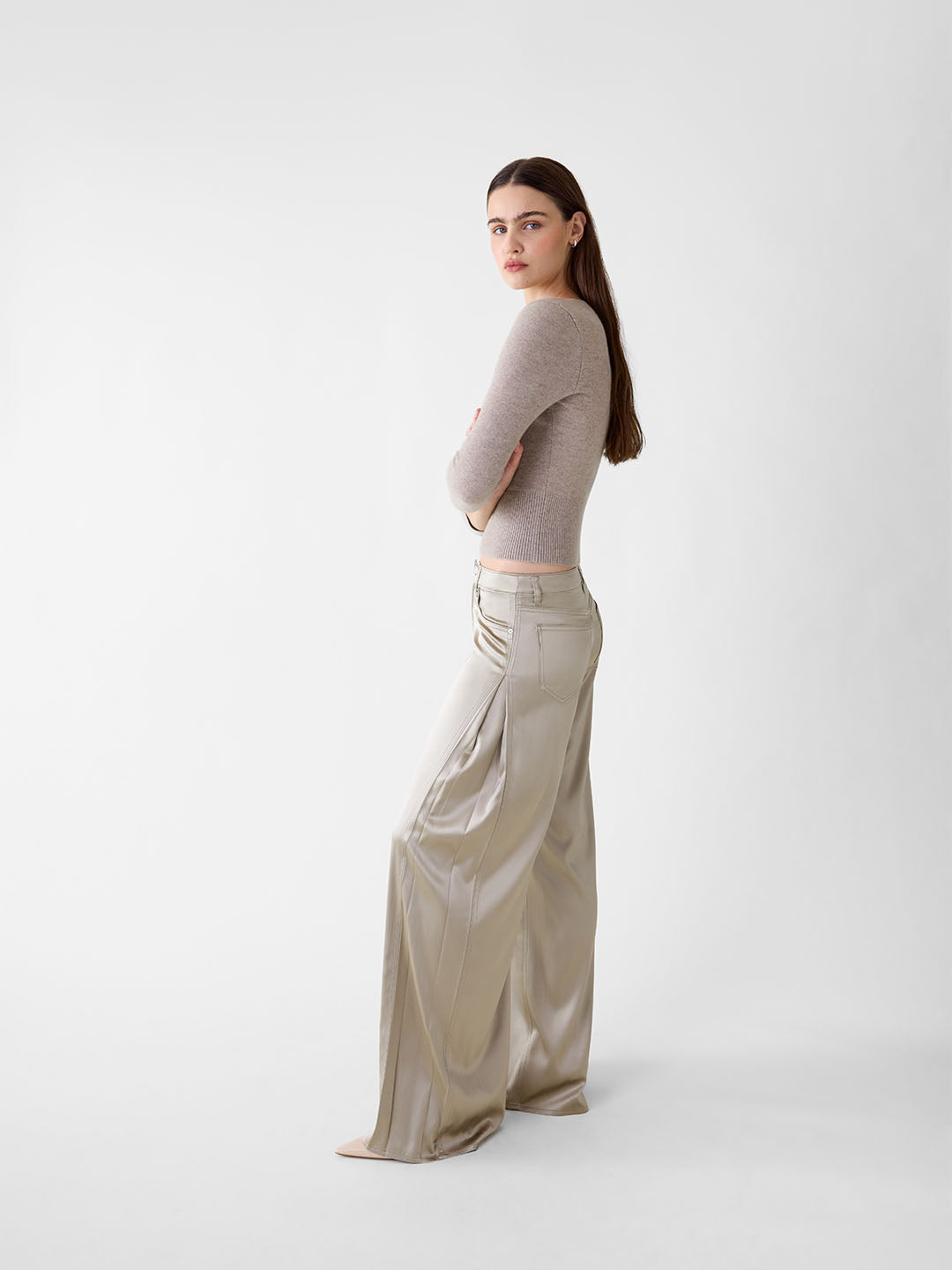 Model wearing khaki stretch silk wide-leg jeans with side pleats and five-pocket denim styling.