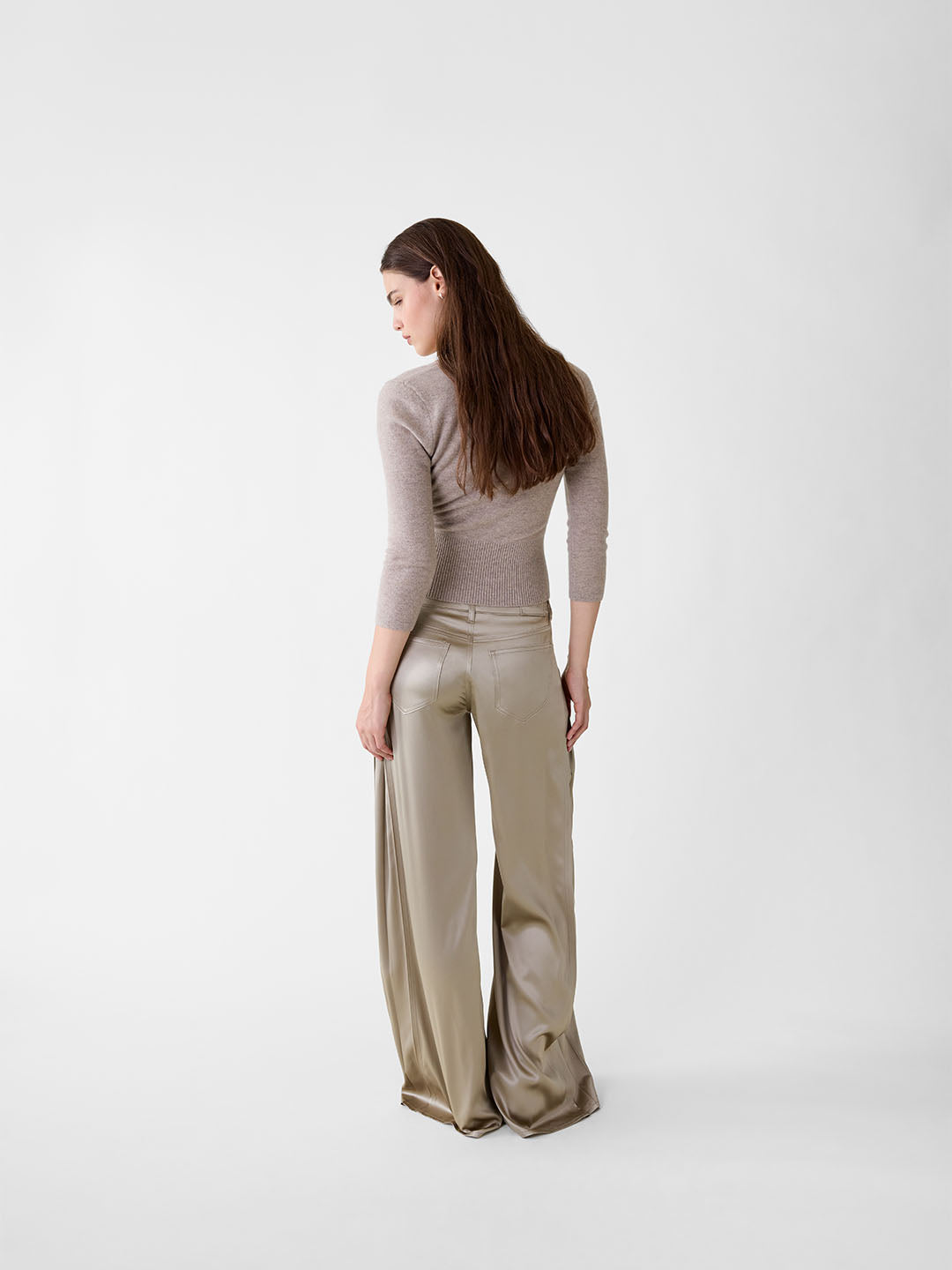 Back view of model wearing khaki stretch silk wide-leg jeans with five-pocket styling and a fluid, relaxed fit.