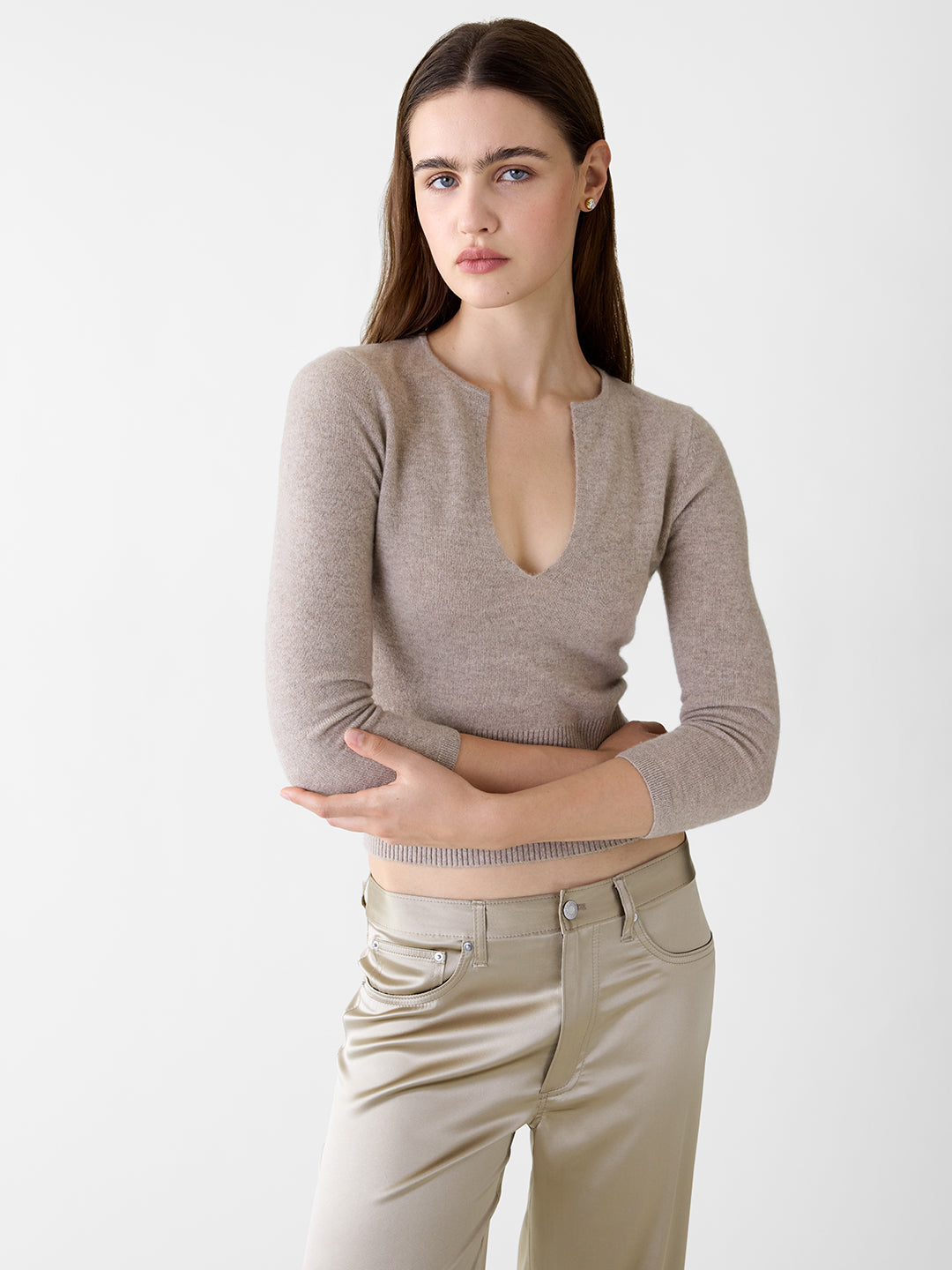 Khaki cashmere sweater with a deep v-neck, three-quarter sleeves, and a ribbed waist, paired with satin trousers.