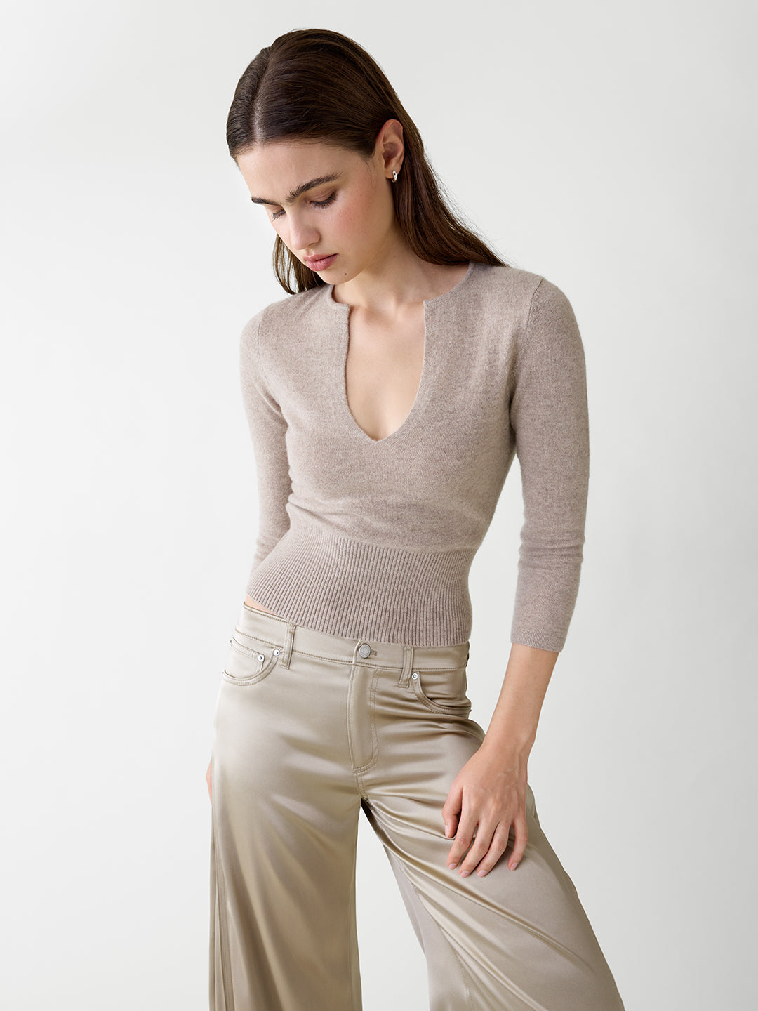 Khaki cashmere sweater with a deep v-neck, three-quarter sleeves, and a fitted ribbed waist on a model.