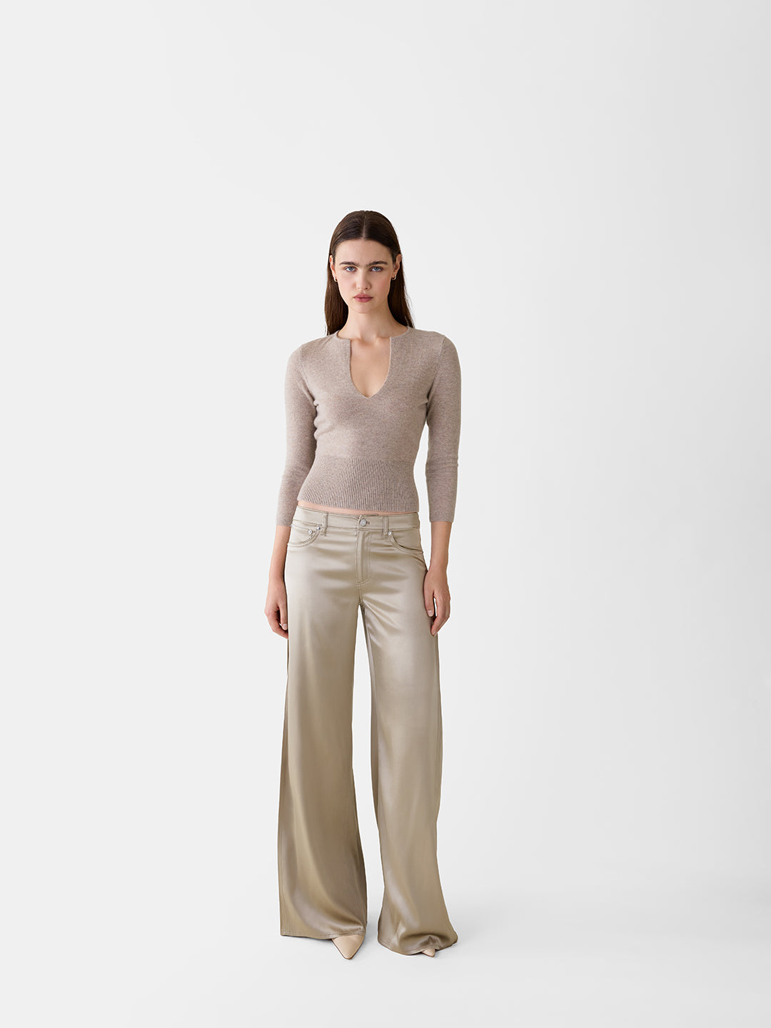 Khaki cashmere sweater with a deep v-neck, three-quarter sleeves, and a ribbed waist paired with satin wide-leg trousers.
