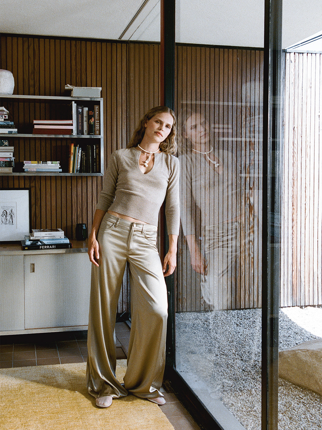 Khaki Romy cashmere sweater with a deep v-neck, three-quarter sleeves, and a ribbed waist, paired with wide-leg trousers.