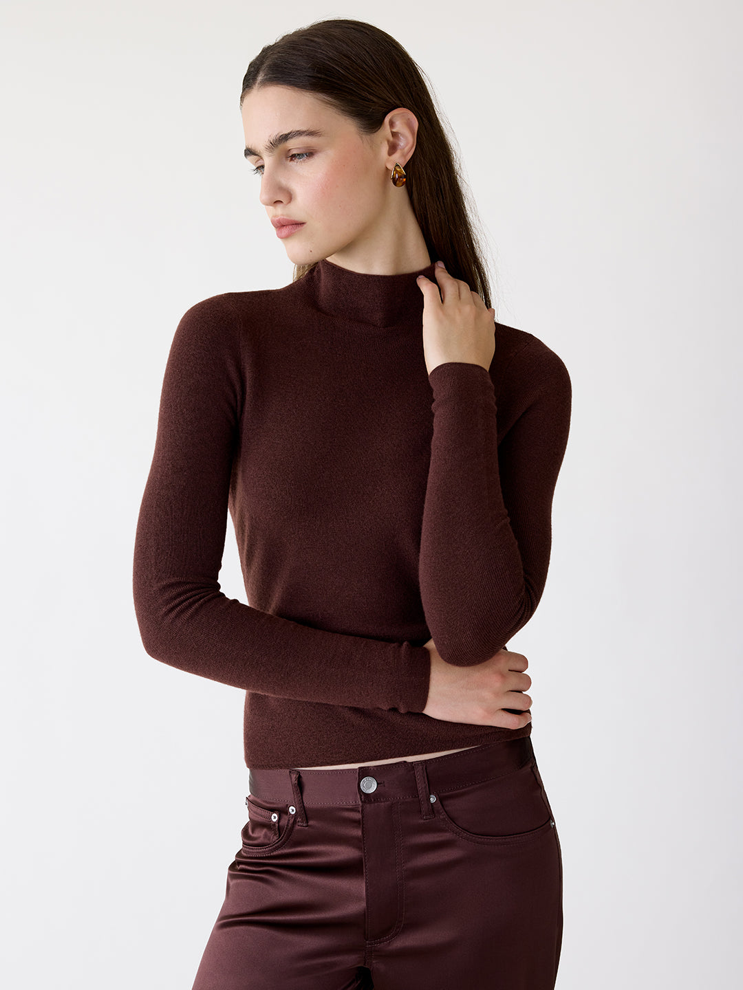 Model wearing a chocolate brown, lightweight cashmere turtleneck sweater with a sculpted, fitted silhouette.