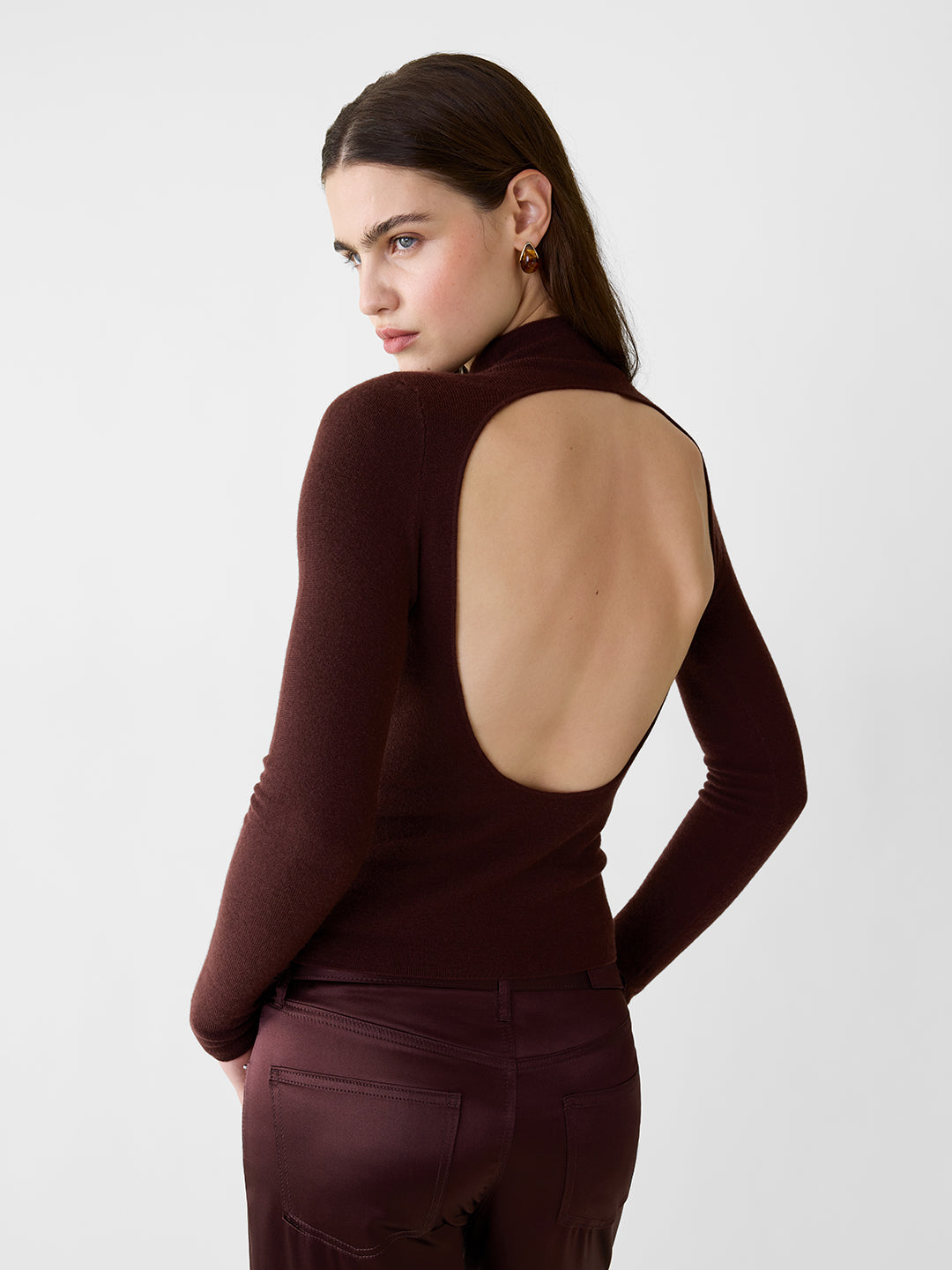 Model wearing a chocolate brown, lightweight cashmere turtleneck sweater featuring a sculpted fit and open back.