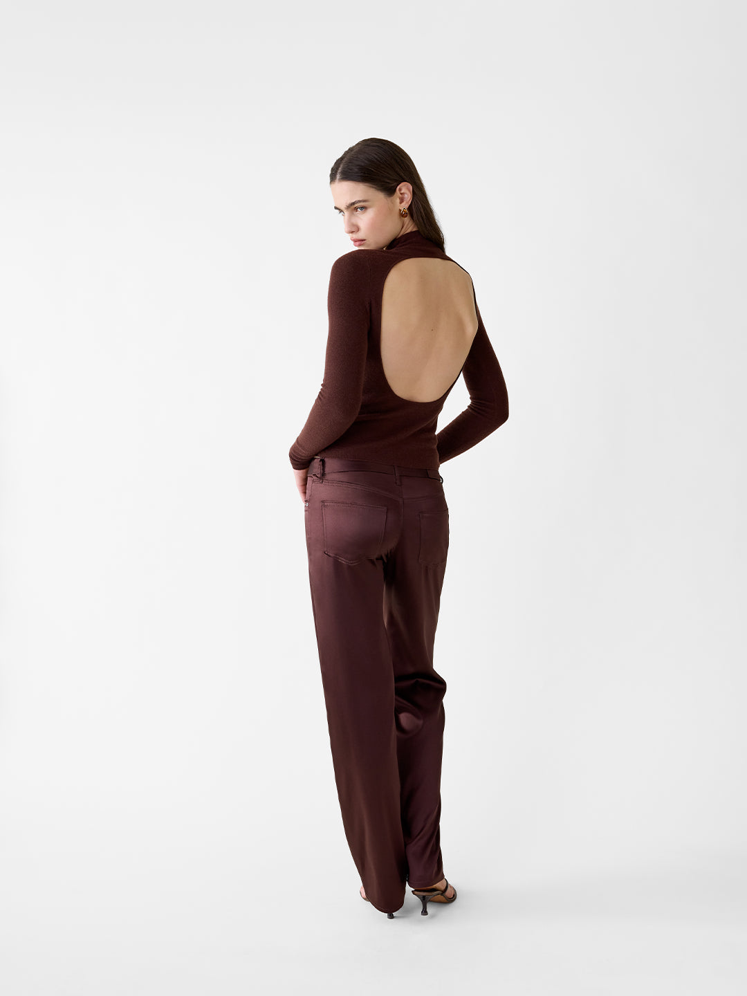 Chocolate brown cashmere turtleneck sweater with an open back, styled with matching satin trousers.