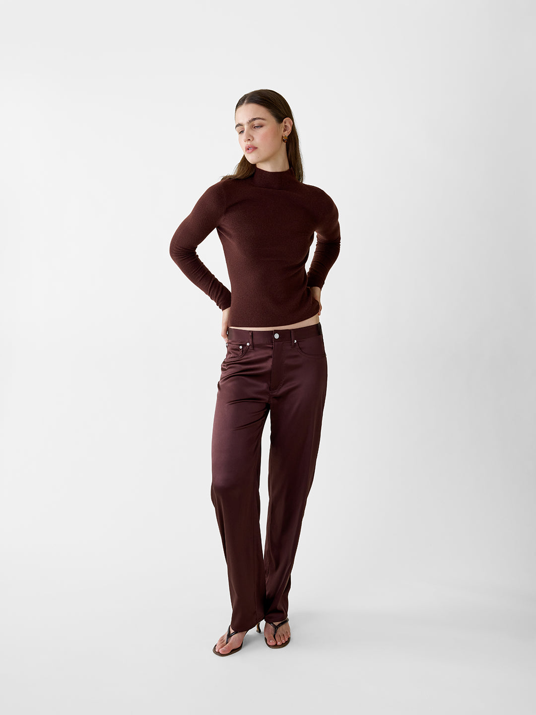 Model wearing a chocolate brown lightweight cashmere turtleneck sweater with a sculpted, fitted silhouette.