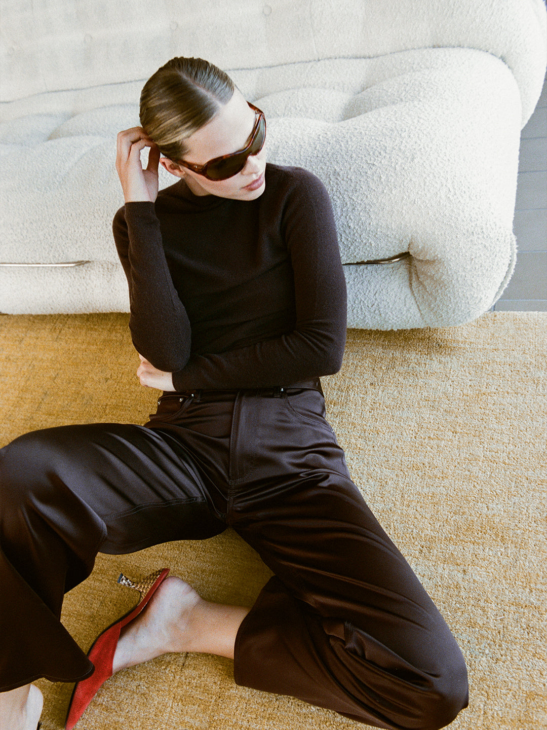 Model wearing a chocolate brown lightweight cashmere turtleneck sweater with a sculpted fit.