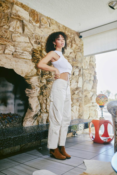 girl standing up wearing mizawe berlin pant in white with gold ring piercings