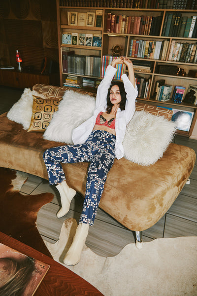 girl sitting down in mizawe reno pant in playing cards print with arms stretched up